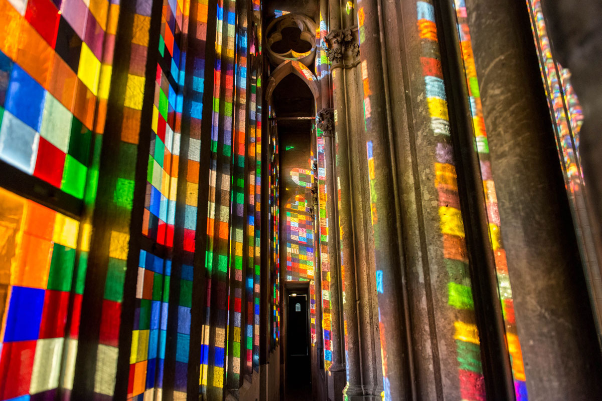 Farbige Lichtflecken des Richter-Fensters auf Pfeilern und Wänden im Inneren des Kölner Doms.